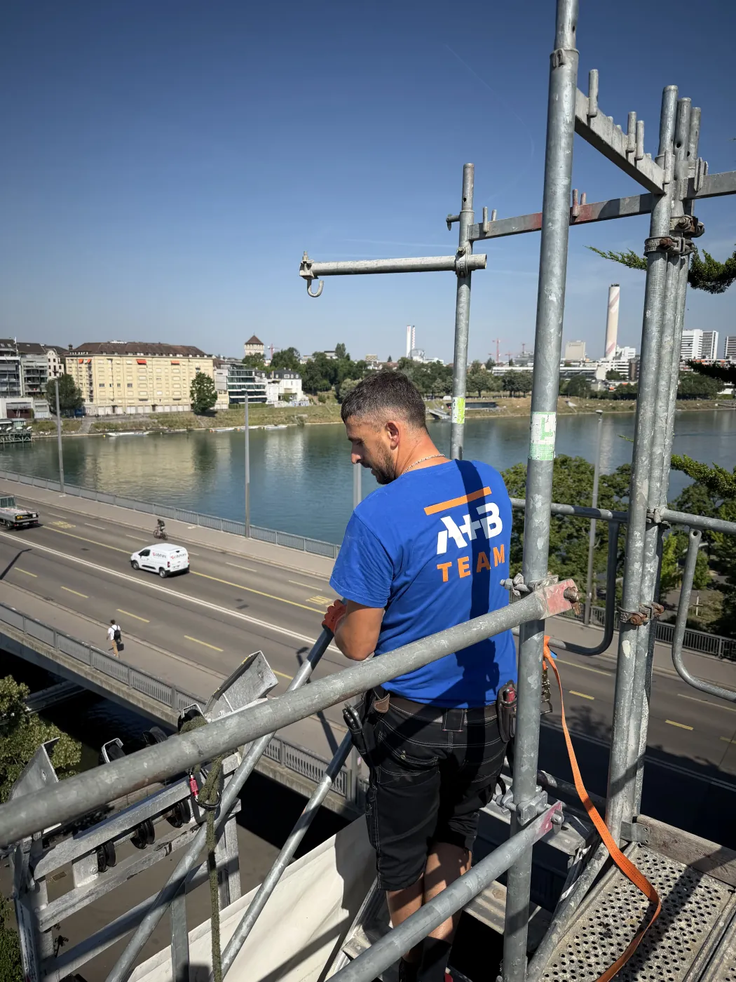 A+B Flachdach Teammitglied bei der Arbeit auf dem Gerüst mit Blick über den Rhein in Basel